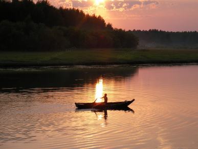 Muž v člne pri západe slnka
