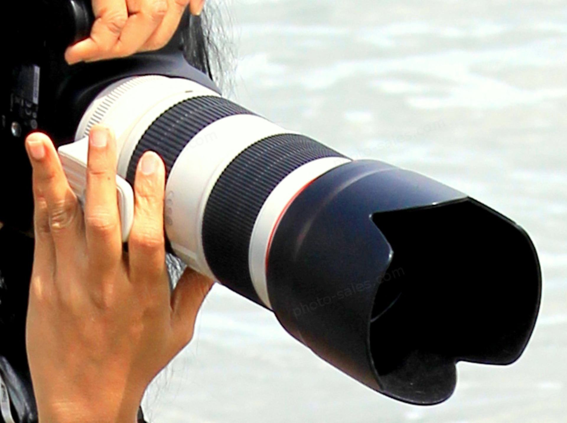 Photo camera with large lens in hands